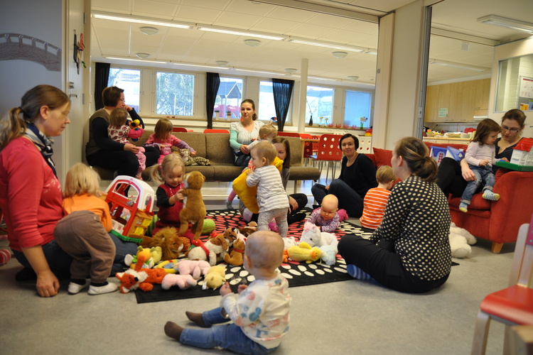 Pienet perhekerholaiset ja heidän äitinsä leikkimässä nalleilla